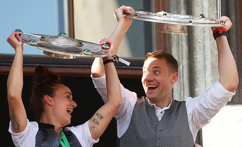 Lina Magull und Manuel Neuer zeigen die Meisterschalen auf dem Rathausbalkon.