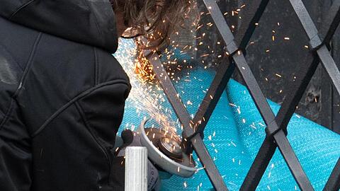 Mitarbeiter einer Restaurierungsfirma arbeiten mit einem Winkelschleifer am durchtrennten Gitterfenster des Grünen Gewölbes.