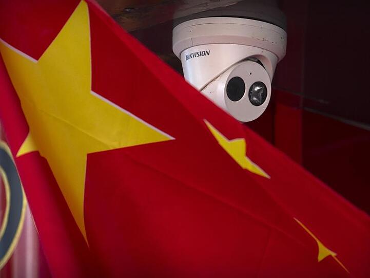Eine chinesische Flagge weht neben einer Sicherheitskamera der Firma Hikvision in Peking.